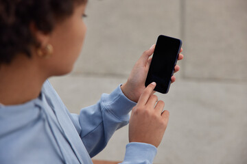 Cropped shot of unrecognizable woman holds mobile phone with empty copy space screen for your advertising content chats on cellular. Digital mobile phonewith copy space area for website info