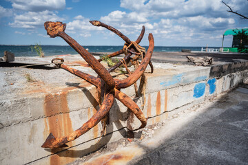Old rusty marine anchor on the pier close up background.