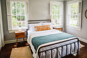 A guest bedroom with a queen sized bed and nightstand at a short term rental small cottage style house - Powered by Adobe