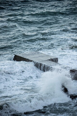 Fototapeta premium Sea waves break on a concrete pier. Breakwater.