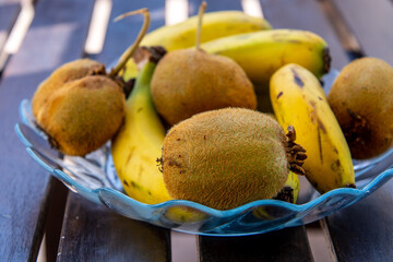 Plátanos y kiwis en un plato de cristal sobre una mesa de madera