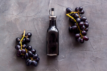 Red wine vinegar in glass bottle with bunch of black grapes