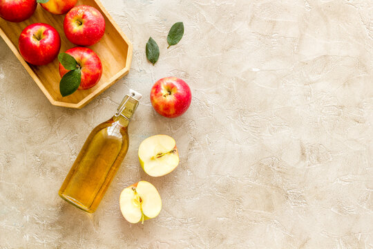 Homemade apple cider vinegar in glass bottle with red apples
