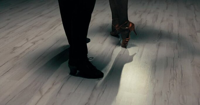 A shot of the dancers' legs, shapely legs of a woman in gold stilettos and black cabaret tights move sexily, gently, nimbly, a girl dancing with a partner in slippers