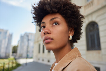 Photo of good looking young woman with Afro hair dressed in stylish clothes looks into distance...
