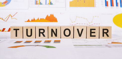 On a light background, graphs, diagrams and wooden cubes with the word TURNOVER.