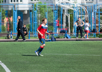 Obraz premium Young sport boys in red sportswear running and kicking a ball on pitch. Soccer youth team plays football in summer. Activities for kids, training 