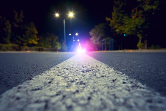 Focus On City Road With Blurred Police Car Red And Blue Lights In The Distance, Crime And Accident Concept