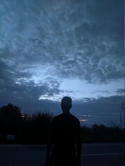 silhouette of man standing in front of clouds