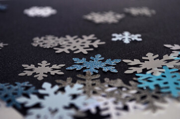 Pequeños copos de nieve de papel, gama de colores fríos, con glitter, brillos en fondo azul oscuro