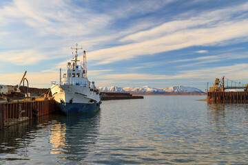 The passenger motor ship is moored near the berth in the seaport. Beautiful marine arctic landscape. View of the ship, pier, sea and mountains. Transport infrastructure. Beringovsky, Chukotka, Russia.