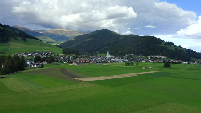 Church of San Giovanni Battista, Dolomites, Toblach, Dobbiaco, Puster Valley, Bolzano, South Tyrol, Italy, September 2021. Drone pushes towards the town with the copper roof church in the center.