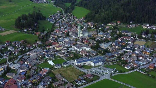 Church of San Giovanni Battista, Dolomites, Toblach, Dobbiaco, Puster Valley, Bolzano, South Tyrol, Italy, September 2021. Drone orbits from the south with the copper roof church in the center.