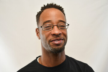 African American male wearing glasses looks into the camera with a smile. 