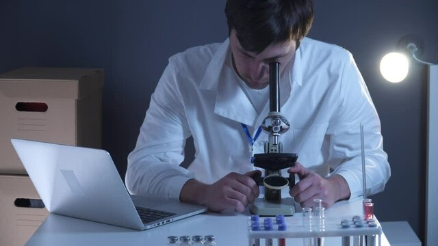 Scientist at workspace in laboratory with microscope, computer, and laboratory tools. Bio technology. Med students stuff. Medical assistant. Scientific research. Checking results on laptop in lab.
