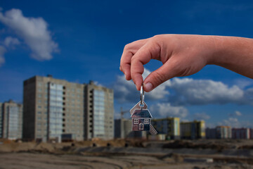 Man holds the keys to the house in his hands against the background of a multi-storey building. Concept for buying and renting apartments.