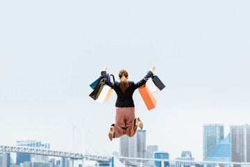 買い物袋を沢山持ってジャンプする女性（セール・爆買い）