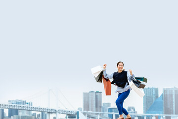 買い物袋を沢山持ってジャンプする女性（セール・爆買い）