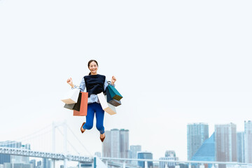 Fototapeta na wymiar 買い物袋を沢山持ってジャンプする女性（セール・爆買い）