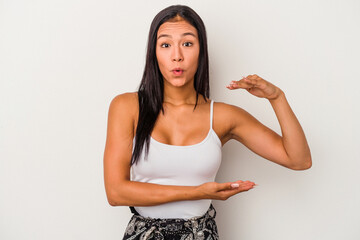 Young latin woman isolated on white background  shocked and amazed holding a copy space between...