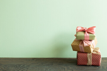 Stack of colorful gift boxes on wooden table. green wall background