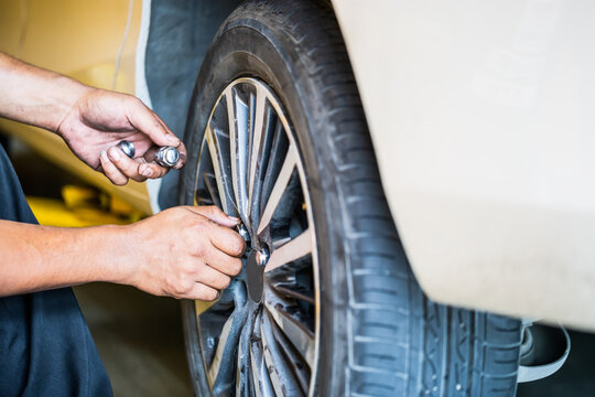 Repair mechanic hands during maintenance work to loosen a wheel nut changing tyre of car, man fixing repairing car wheel vehicle parts in garage