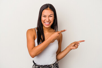 Young latin woman isolated on white background  pointing with forefingers to a copy space, expressing excitement and desire.