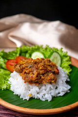 Sambal Peda, Indonesian Traditional Food with white rice, tomatoes, cucumber, and lettuce on wooden plate decorated with golden cloth