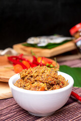 Sambal Peda, Indonesian Traditional Food in white bowl decorated with chiles and tomatoes on wooden table