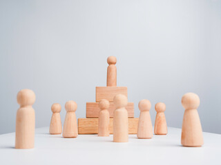 Leadership concept. The Leader or influencer, a wooden human standing on the top of a podium block with other wood humans, followers on white background, minimal style.