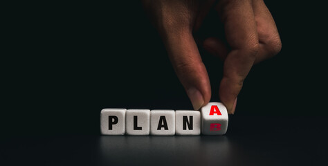 Hand flipping the white dice blocks with plan A change to backup plan B on dark background. Concept...