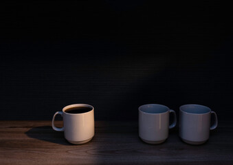 Tres tazas de café sobre mesa de madera con fondo oscuro