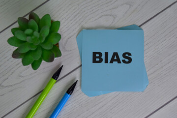 Bias write on sticky notes isolated on Wooden Table.