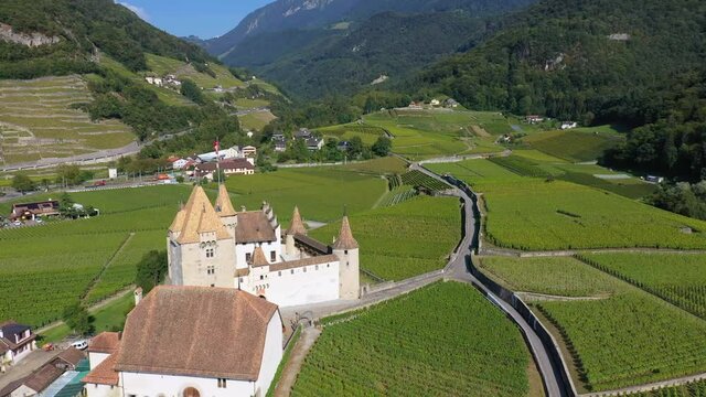 Aerial drone footage of the Aigle castle in the middle of vineyards in Canton Vaud in Switzerland with a backward and tilt down motion
