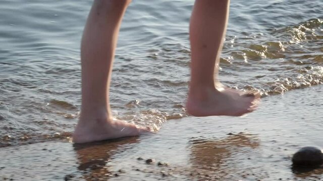 Barefoot kids legs feet walking on beach ocean water. Summer vacation, holiday, family trip. Tourism to warm countries.