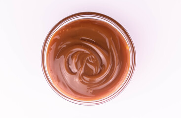 Bowl of sweet caramel sauce on a white plate, top view.