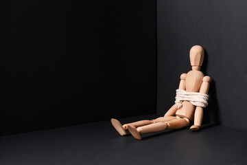 Mannequin with tied around rope on dark background. Concept of hostage