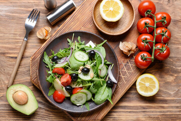 Plate with healthy salad with olives on wooden background