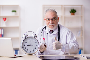 Old male doctor in time management concept