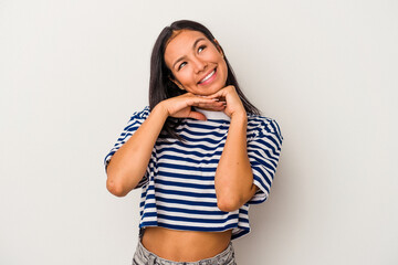 Young latin woman isolated on white background  keeps hands under chin, is looking happily aside.