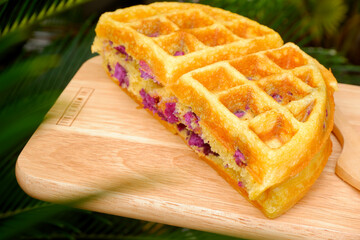 Purple sweet potato flavor delicious waffles on the wooden plate.