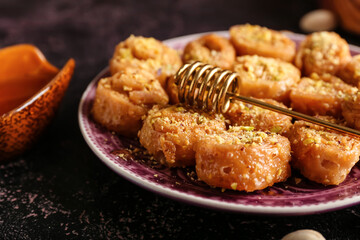 Plate with delicious baklava and honey dipper stick, closeup