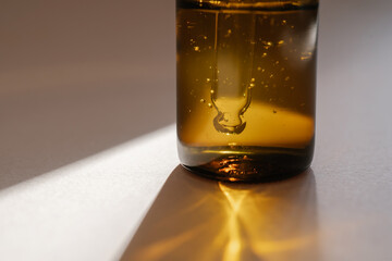 A brown bottle of serum against the beige background..