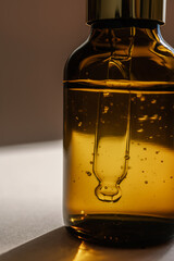 A brown bottle of serum against the beige background..