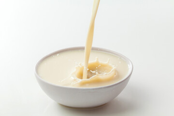 soy milk pouring into bowl on white table.