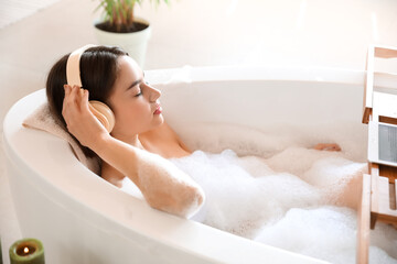 Young woman listening to music while taking bath at home