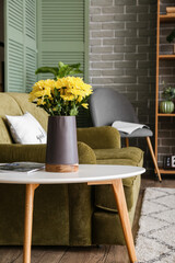 Chrysanthemums in vase on table in interior of cozy living room