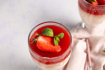 Tasty homemade panna cotta with strawberry and mint in glass on light background, closeup