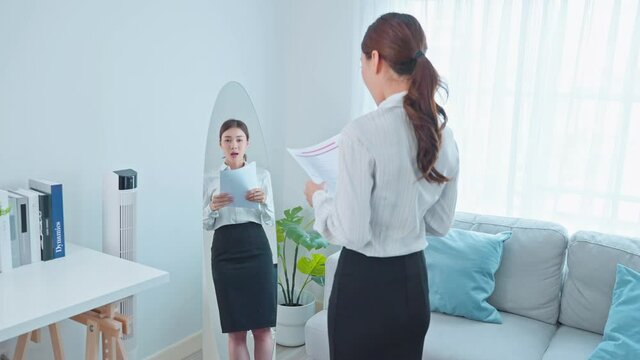 Asian applicant prepare for job interview in front of mirror at home.
