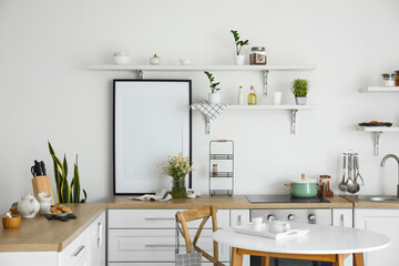 Fototapeta na wymiar Stylish decor in light kitchen interior with blank poster frame